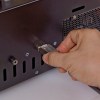 A hand plugs a large silver connector into the back panel of an MTC Series SATA/IDE HDD/SSD Daisy-Chain High Speed Duplicator and Sanitizer 1-15, which features ventilation holes and multiple ports for managing several drives.